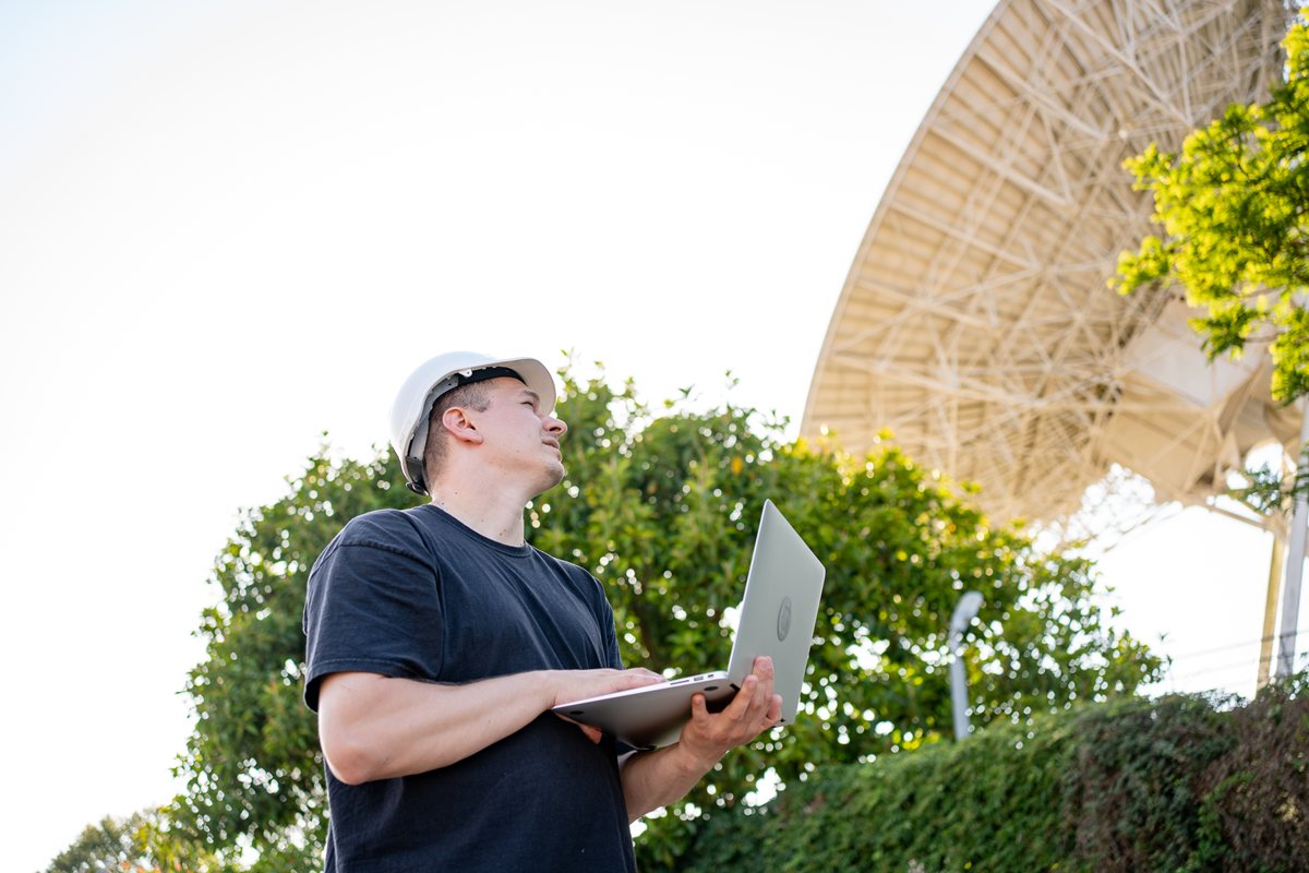 Surveyor looking at satellite - Understanding GNSS in Topographic Surveying: Accuracy at Scale